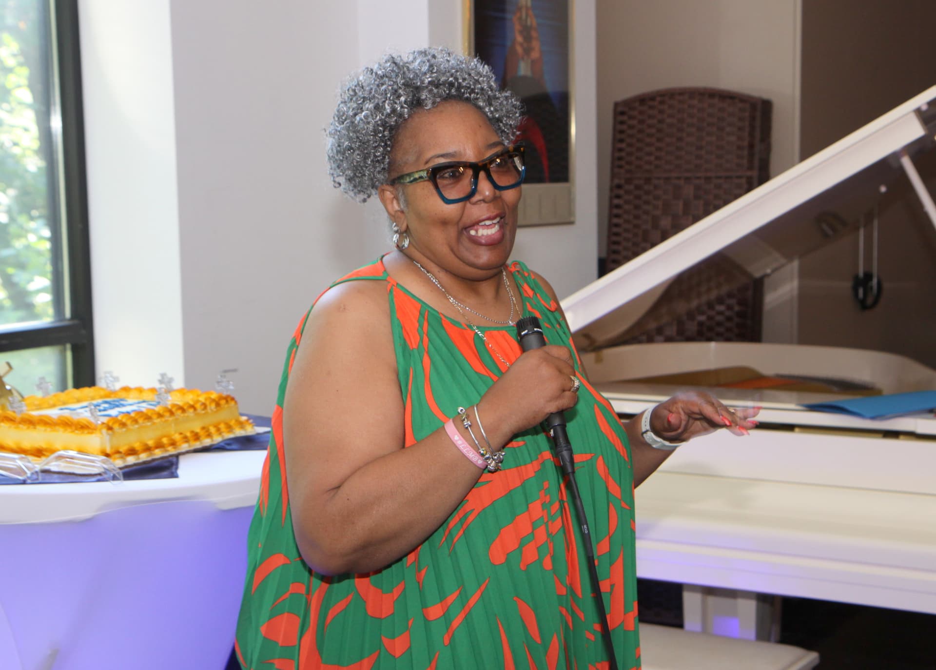 A guest speaking on the microphone beside the birthday cake