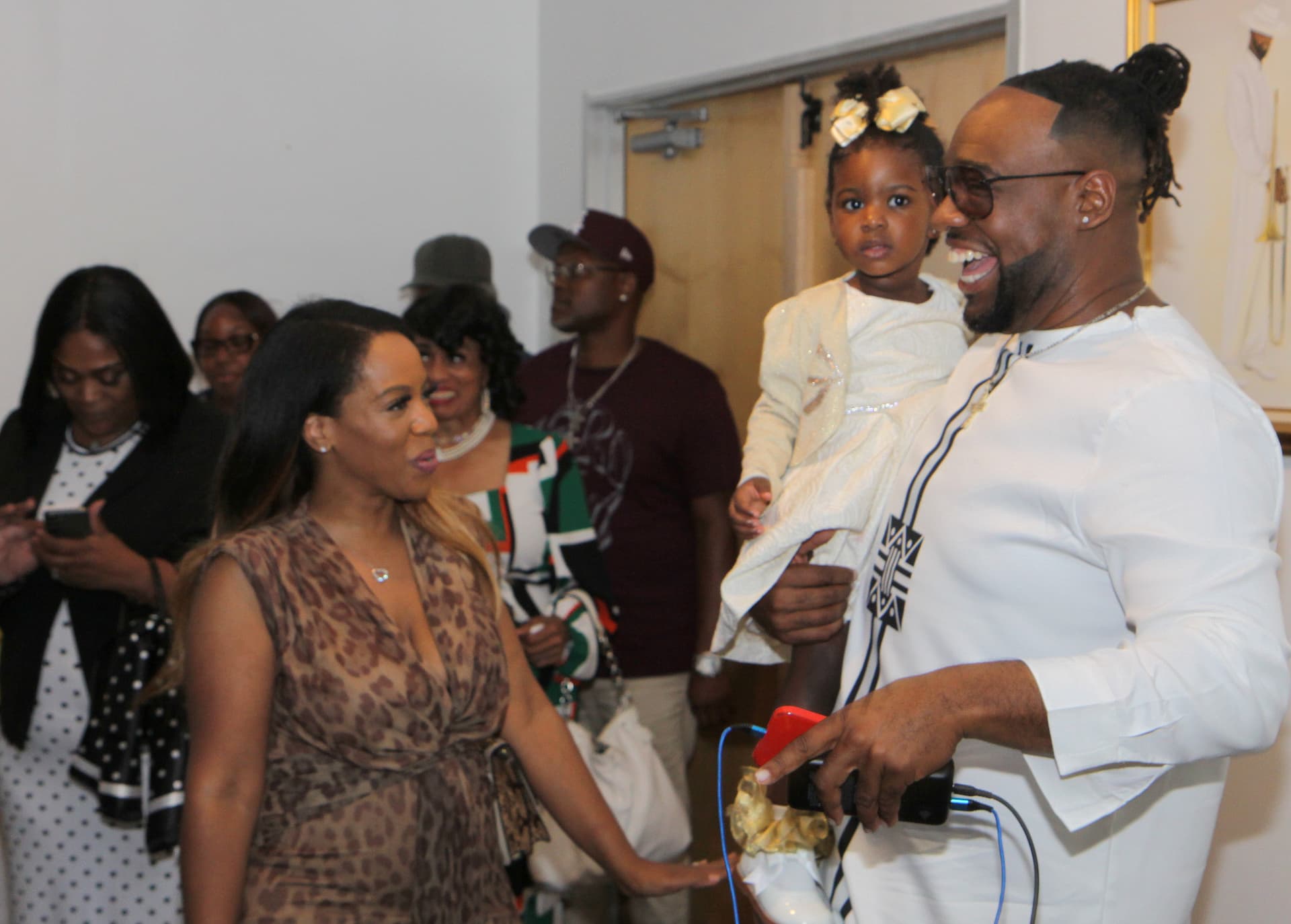 Guests laughing together, one holding a little girl in white