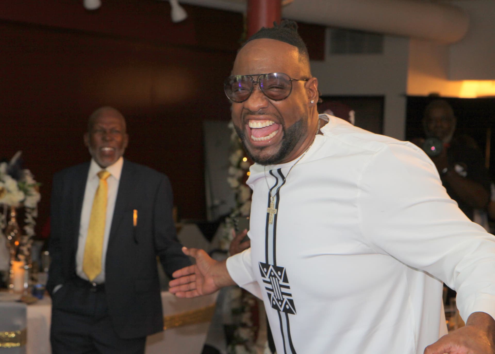 Pastor Lo laughing with arms outstretched during the celebration