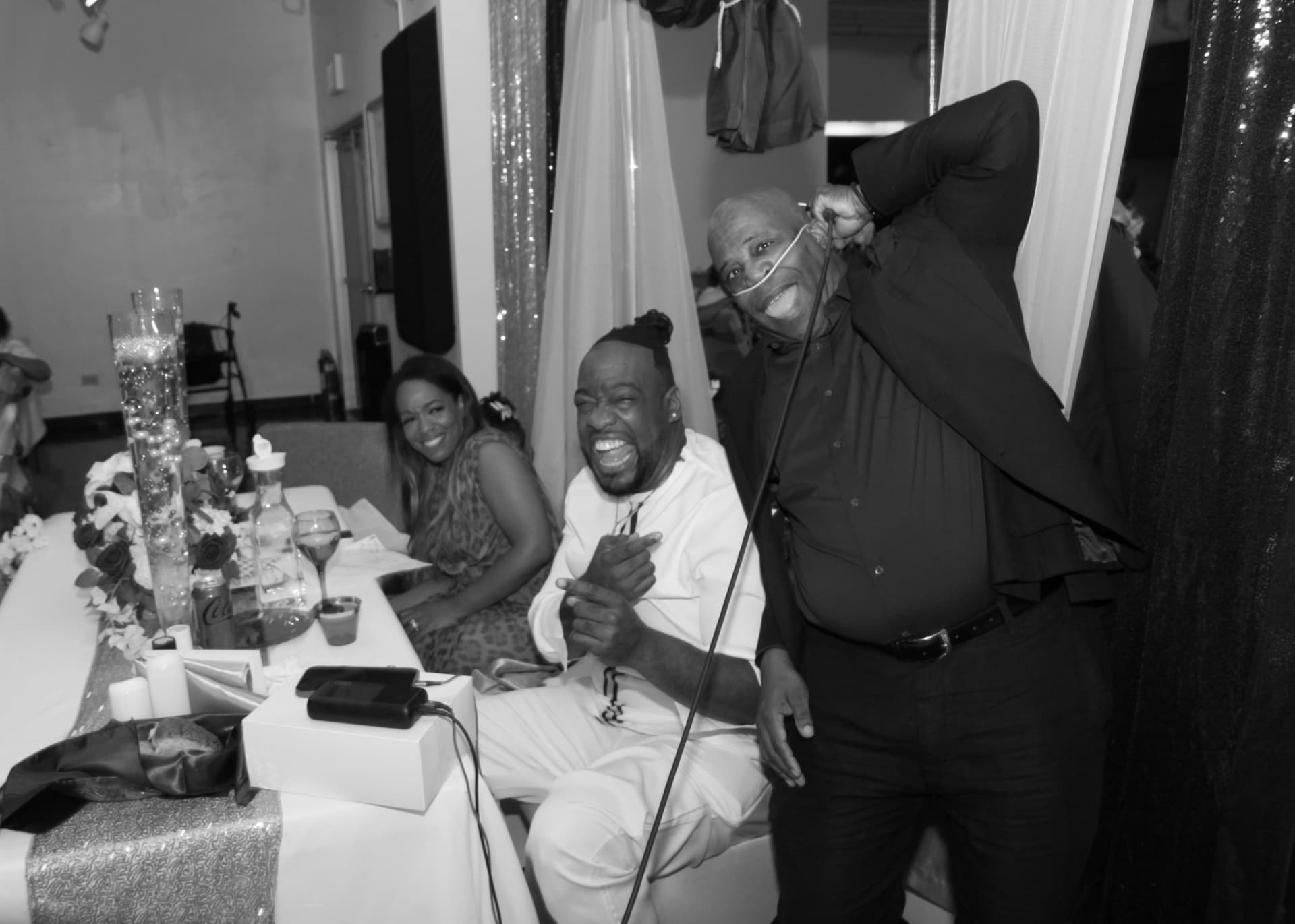 Black and white photo of Pastor Lo laughing with guests at the head table