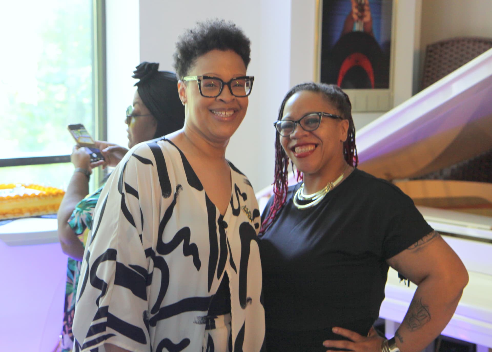 Two guests smiling together near the piano at the celebration
