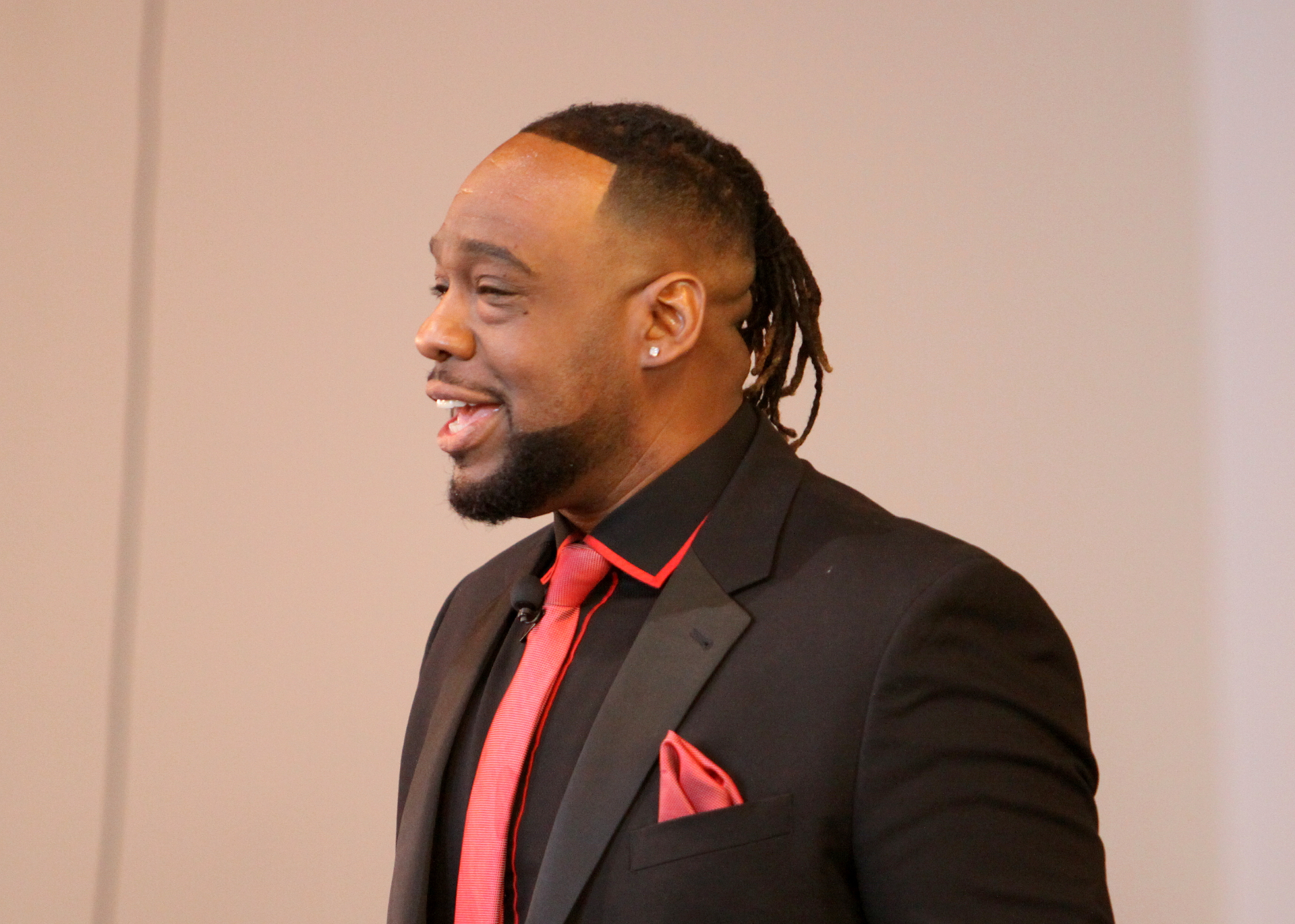 Minister in black suit and red tie smiling during service