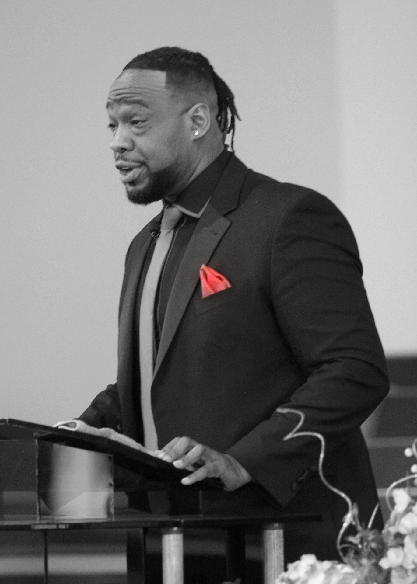 Minister speaking at the pulpit in black and white with red accents